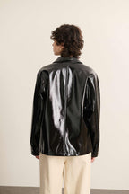 Set bagfra af vinyljakken, fremstillet i 100 % polyester, med en ensartet glans over hele overfladen.