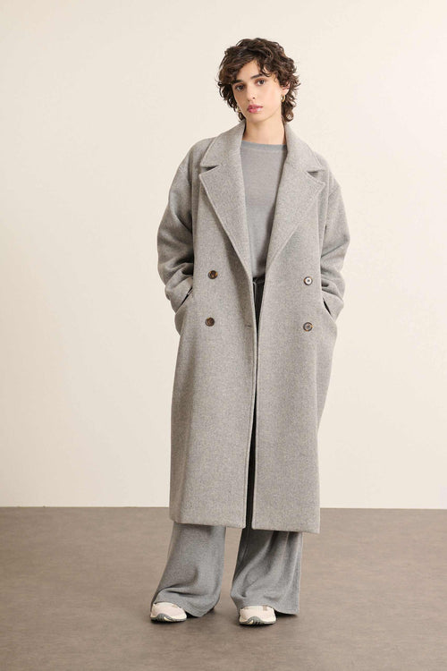 Manteau long coloris gris porté par une femme, à la coupe droite et à l'allure contemporaine style Garance Paris. 