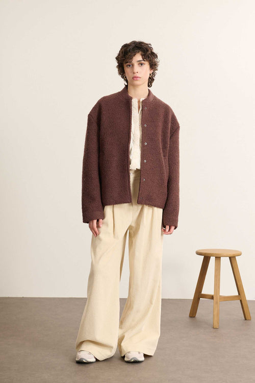 Tissu en laine bouclette mélangée, au toucher dense et irrégulier, coloris marron profond à effet texturé.