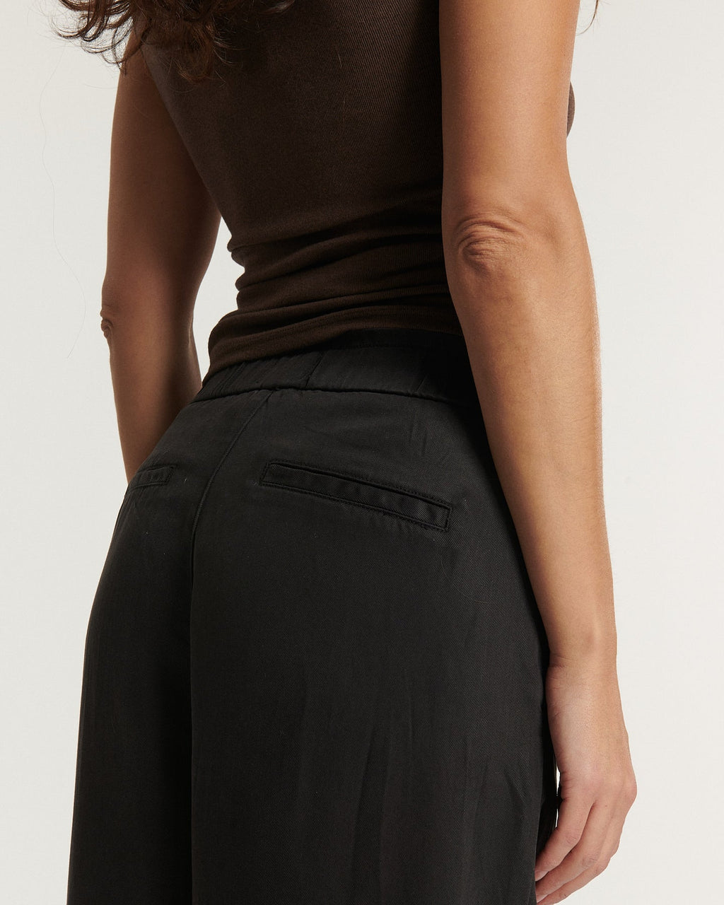 Pantalon femme en tissu Tencel marron foncé, coupe droite et fluide avec poches arrière passepoilées, s'adaptant parfaitement à toutes les morphologies.