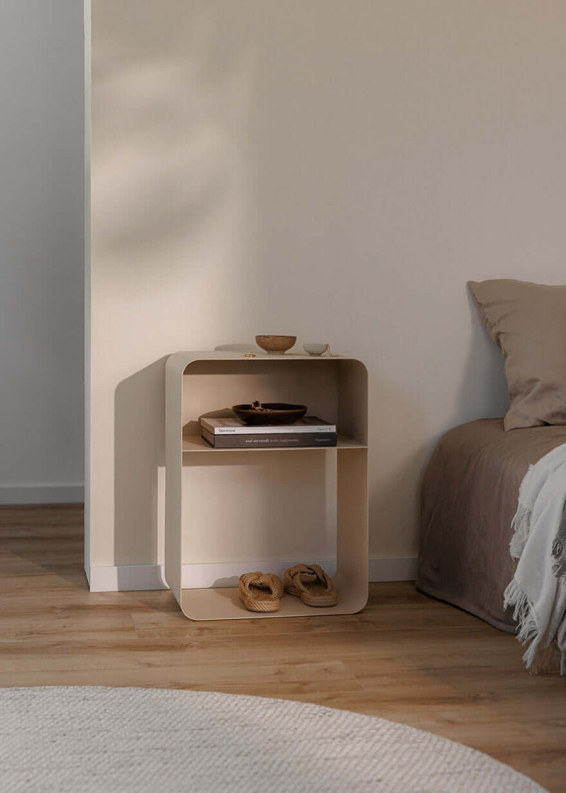 Stehender Nachttisch mit minimalistischen Design, rundenden Formen und pulverbeschichteter Oberfläche in einem modernen Schlafzimmer.
