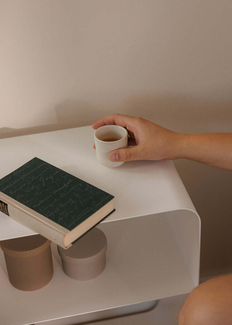 Stehender Nachttisch mit einem Buch und einer Tasse auf der Oberfläche, minimalistische Eleganz im modernen Stil.