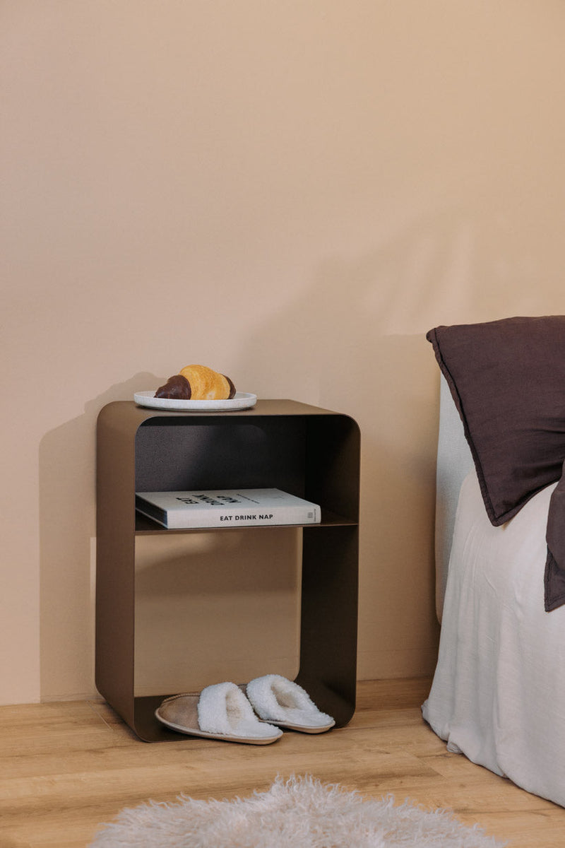 Stehender Nachttisch mit minimalistischen Design, abgerundeten Formen und pulverbeschichteter Oberfläche.