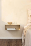 Hängender Nachttisch NELIO in minimalist Formensprache über einem Bett mit Deko-Objekten.