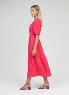 An'ge – Robe Midi Odoumilo Framboise, mannequin femme blonde de profil portant une robe longue rose fuchsia