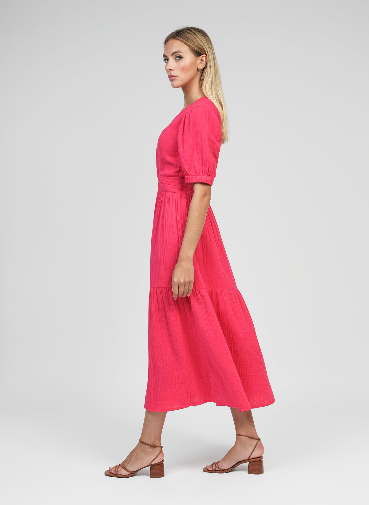 An'ge – Robe Midi Odoumilo Framboise, mannequin femme blonde de profil portant une robe longue rose fuchsia