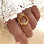 Instants Plaisirs – Bague "Orma" Acier, bague dorée portée au doigt d'une femme, avec une manche en dentelle blanche