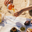 Une nappe posée sur les rochers, quelques olives vertes et oursins, et c'est parti pour les apéros d'été. OSCO L'Original, apéritif bio sans alcool, est le compagnon parfait pour se rafraîchir et savourer ce moment de plaisir.
