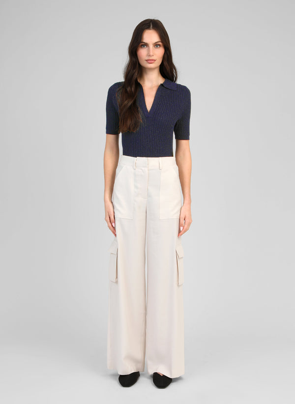 An'ge – Pantalon Pakyla Ecru, vrouwelijk model draagt een marineblauwe top en een beige cargobroek