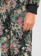 An'ge – Pantalon Passyna Noir, détail d'un pantalon noir à motifs floraux colorés porté par un mannequin