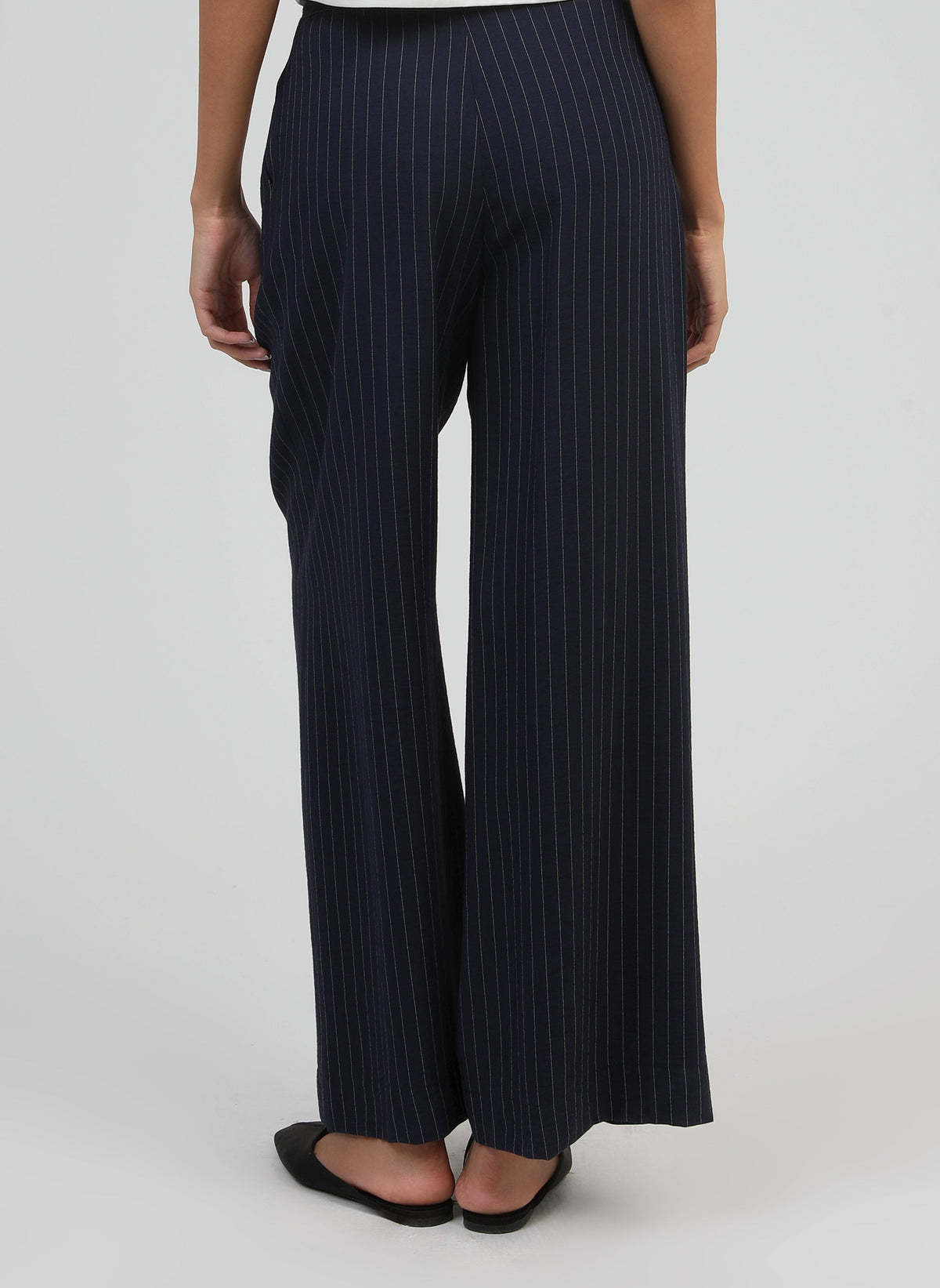 An'ge – Hose Patila Marine, weite marineblaue Hose mit feinen weißen Streifen, von hinten getragen