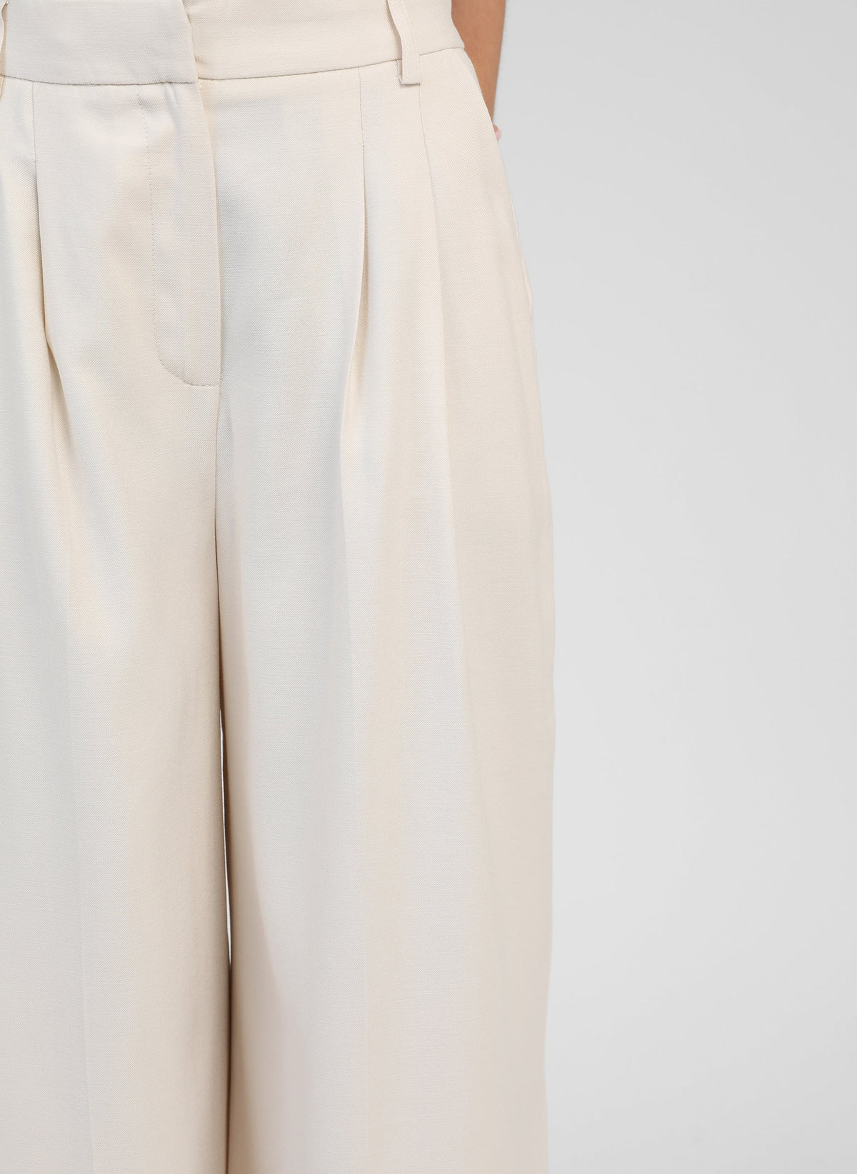 An'ge – Broek Pepy Ecru, wijde lichtbeige plooibroek gedragen door een model