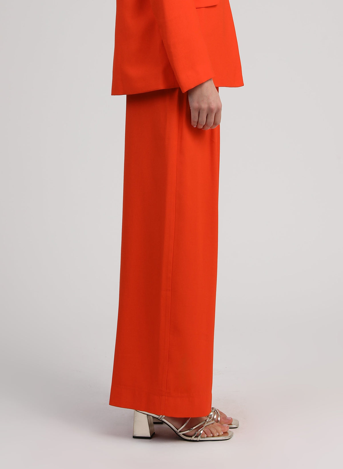 An'ge – Hose Pepy Piment, weite Hose in leuchtendem Orange mit passendem Blazer, getragen von einem Model