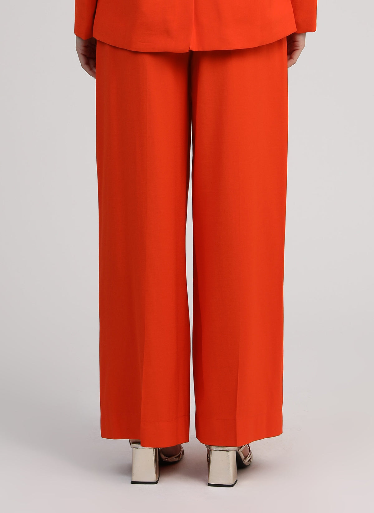 An'ge – Hose Pepy Piment, weite Hose in leuchtendem Orange, von einem Model getragen, Rückansicht