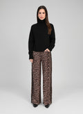 An'ge – Pantalon Perleo Noir, mannequin portant un pull noir et un pantalon léopard, vue de face