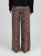 An'ge – Pantalon Perleo Noir, pantalon large à imprimé léopard marron et noir, porté de dos