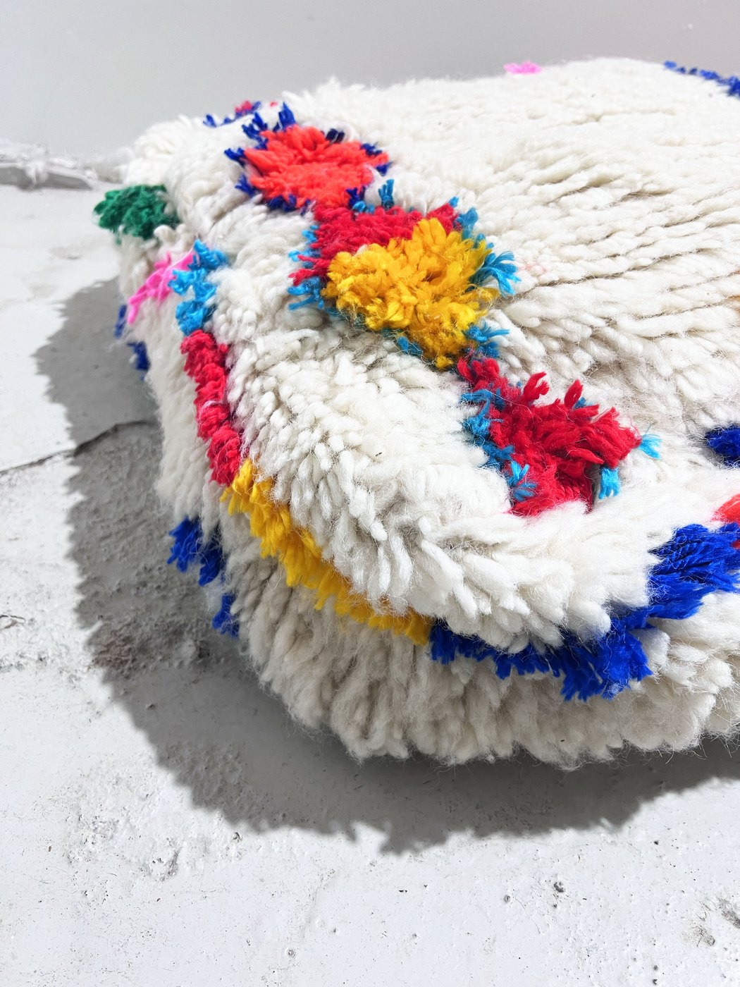 Puf bereber marroquí en crudo con motivos de colores