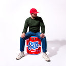 Personne assise sur le coussin géant gonflable OMY Cola – Accessoire pop et fun pour la déco