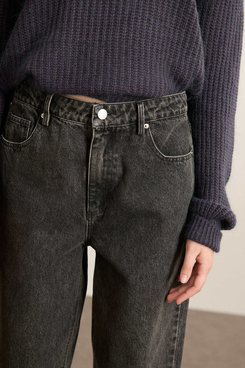 Fermeture par zip métallique et bouton, placés sur une ceinture droite avec passants larges et finitions renforcées.