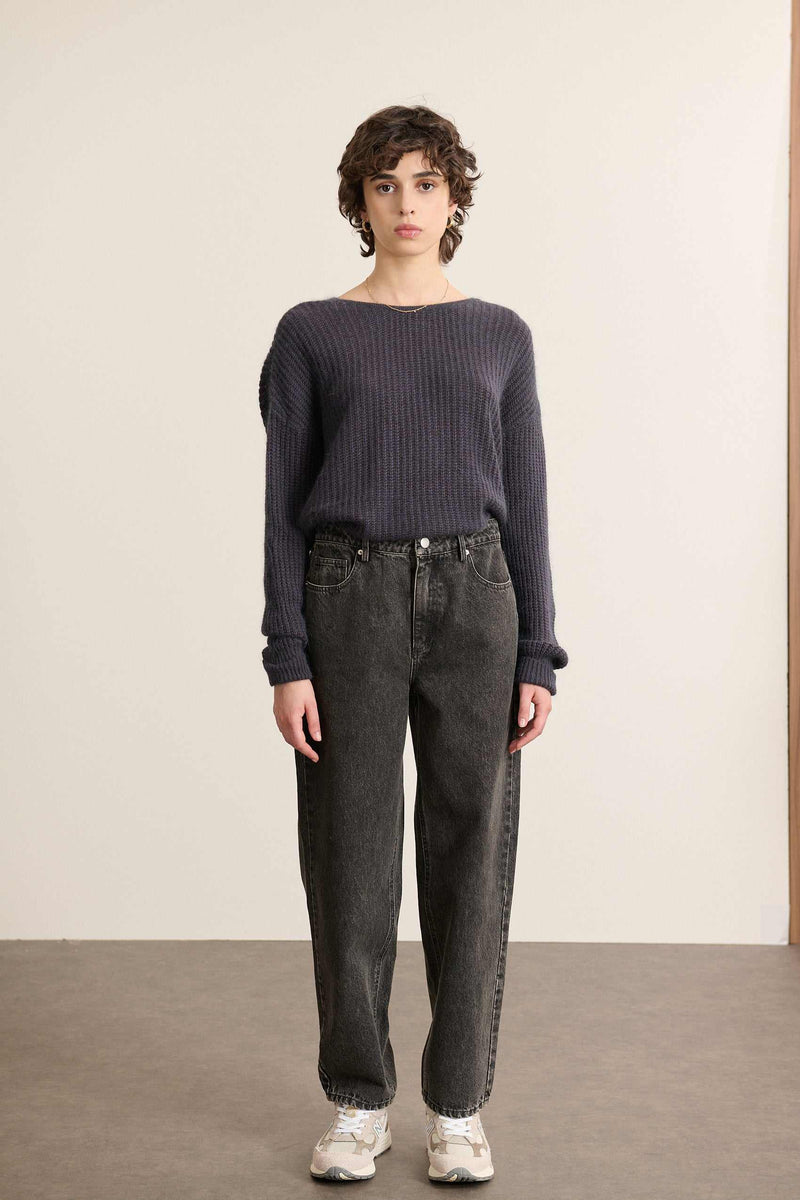 Mannequin femme de face portant un jean coupe ballon coloris gris, taille haute et volume arrondi sur la jambe.