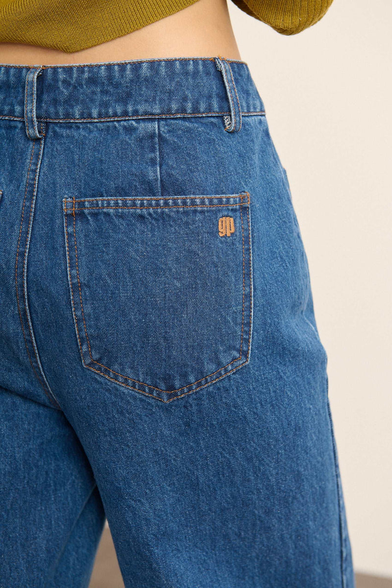 Denim bleu au tissage sergé régulier, matière 100 % coton avec surpiqûres contrastées visibles sur l'ensemble du jean.