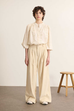 Weibliches Model von vorne in Samthose in Ecru mit weitem Bein, betonter Taille und sichtbaren Bundfalten. 