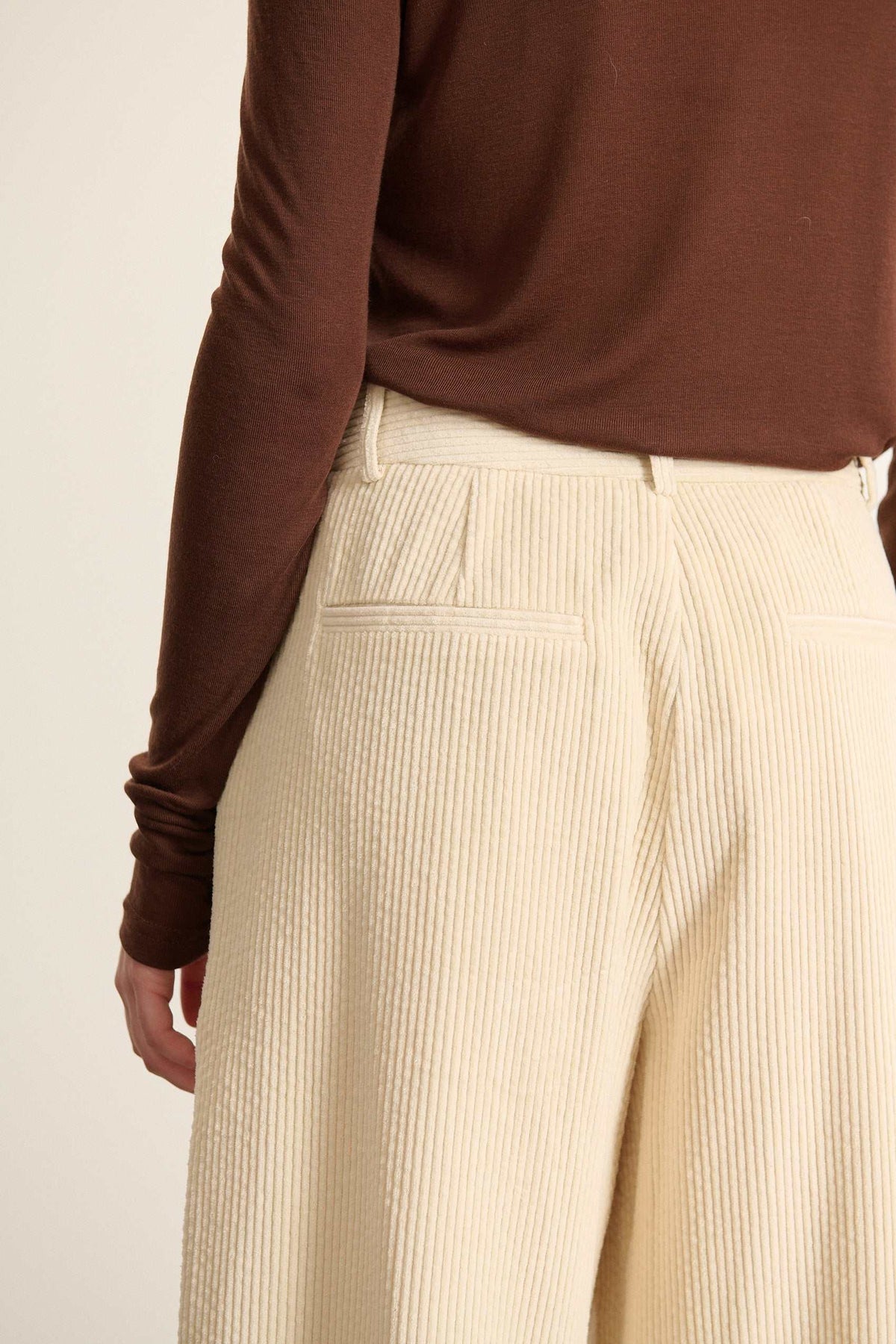 Pantalon à pinces en velours, coupe droite à jambes larges avec poches à l'avant et fermeture par zip et bouton. 