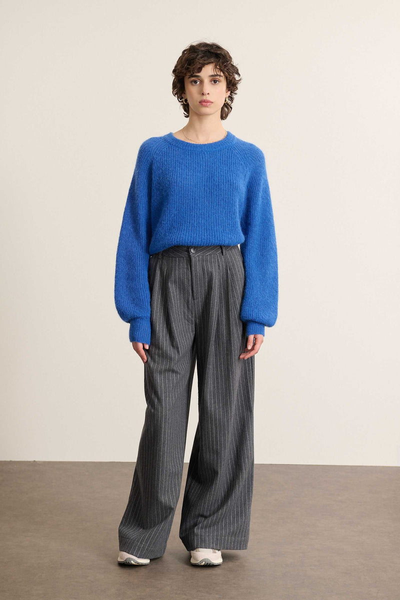 Mannequin femme de face portant un pantalon gris à rayures, jambes larges et taille marquée par des pinces.