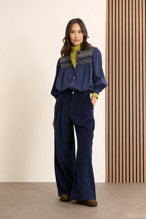 Pantalon à pinces en velours, fermeture par zip et bouton ton sur ton positionnés sur une ceinture plate avec passants.