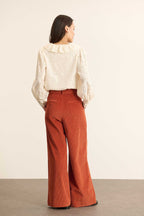 Pantalon à pinces en velours, coupe droite à jambes larges avec poches à l'avant et fermeture par zip et bouton. 