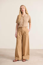 Pantalon élégant  au coloris beige avec jambes larges et taille haute avec passants détails de plis à l'avant 