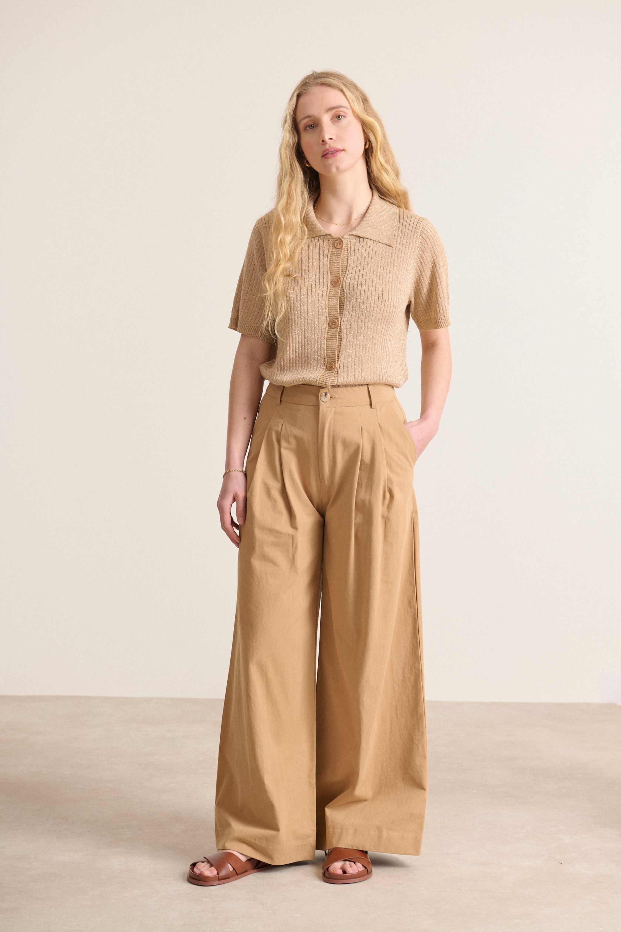 Pantalon élégant  au coloris beige avec jambes larges et taille haute avec passants détails de plis à l'avant 