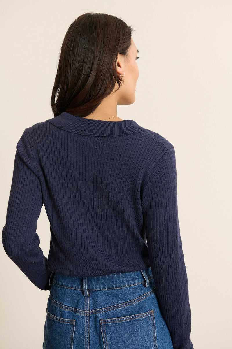 Vue arrière du pull à col polo, coupe droite avec finitions bord-côtes en bas de pièce et couture d’épaule nette.