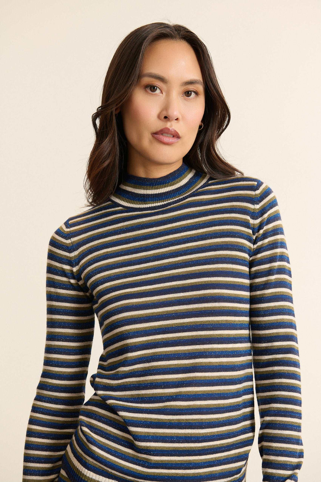 Mannequin femme de face portant un pull bleu à rayures, coupe ajustée avec col montant et manches longues près du corps.