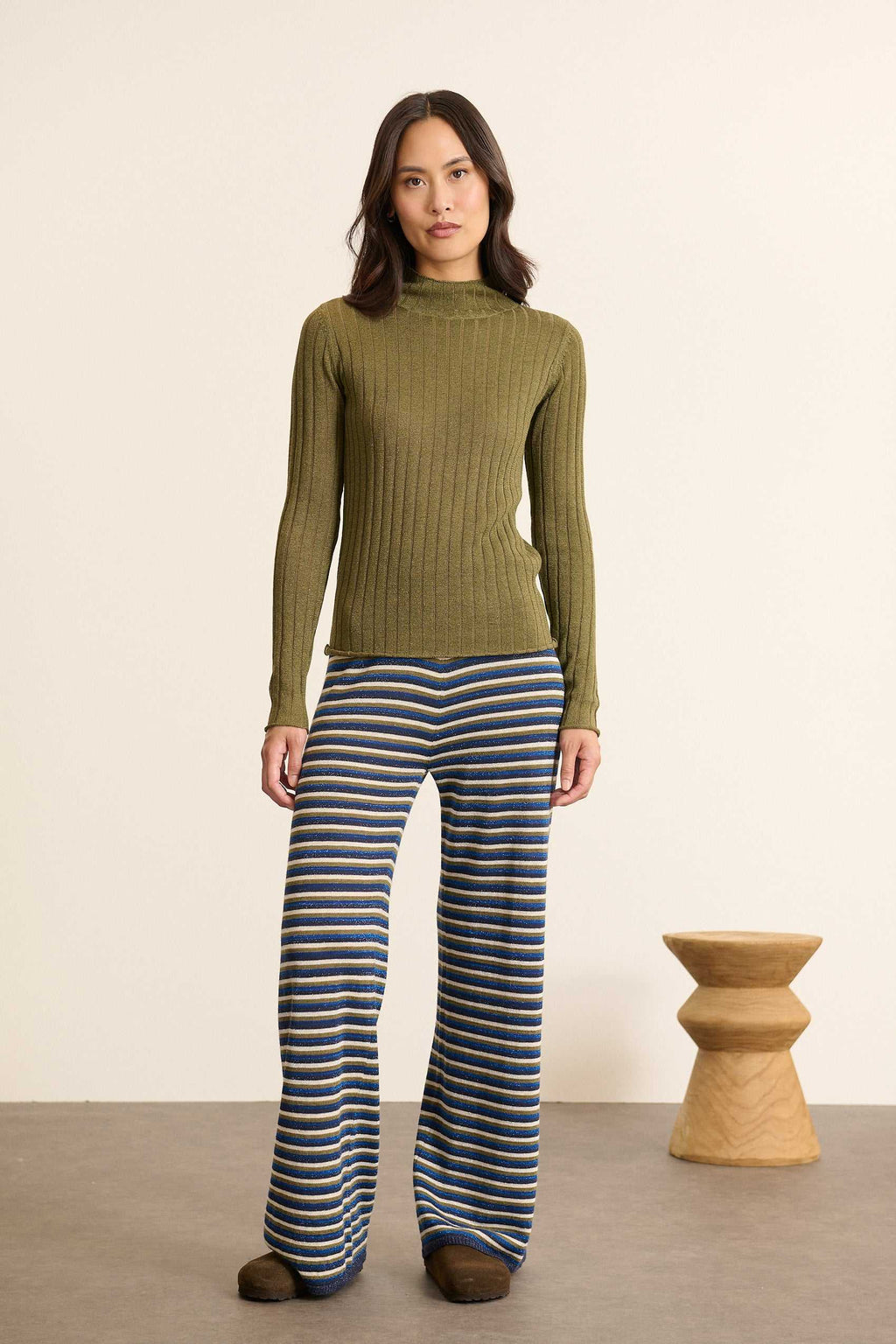 Mannequin femme de face portant un pull kaki à rayures, coupe ajustée avec col montant et manches longues près du corps.