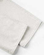 Détail en gros plan d’un jean en denim 100 % coton de couleur granit claire avec une coupe droite et une finition brute au bas des jambes.