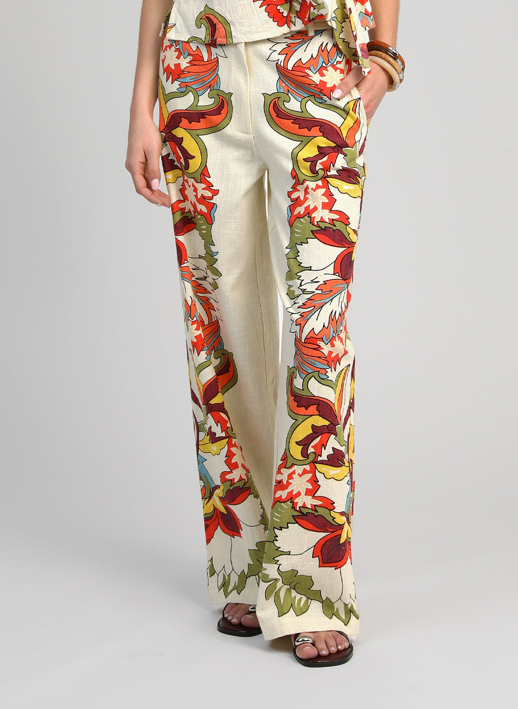 An'ge – Pantalon Rossini Pachama Ecru, wijde écru broek met kleurrijke bloemmotieven, van voren gedragen
