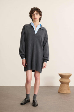 Modella di fronte con abito corto in maglia grigio chiaro, taglio dritto con maniche lunghe e colletto a polo.