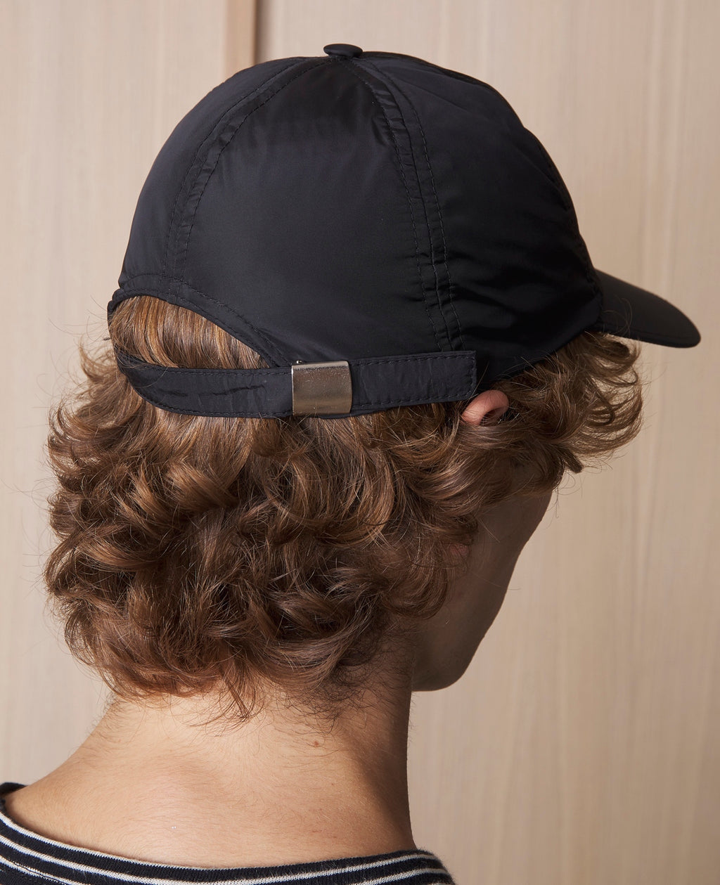 Officine Générale – Casquette Baseball - Noir - Mixte, casquette noire portée de dos par un mannequin aux cheveux bouclés