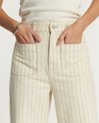 Jean pour femme en denim 100 % coton de couleur sable clair avec rayures subtiles, coupe droite et poches avant larges, offrant un ajustement confortable et moderne.