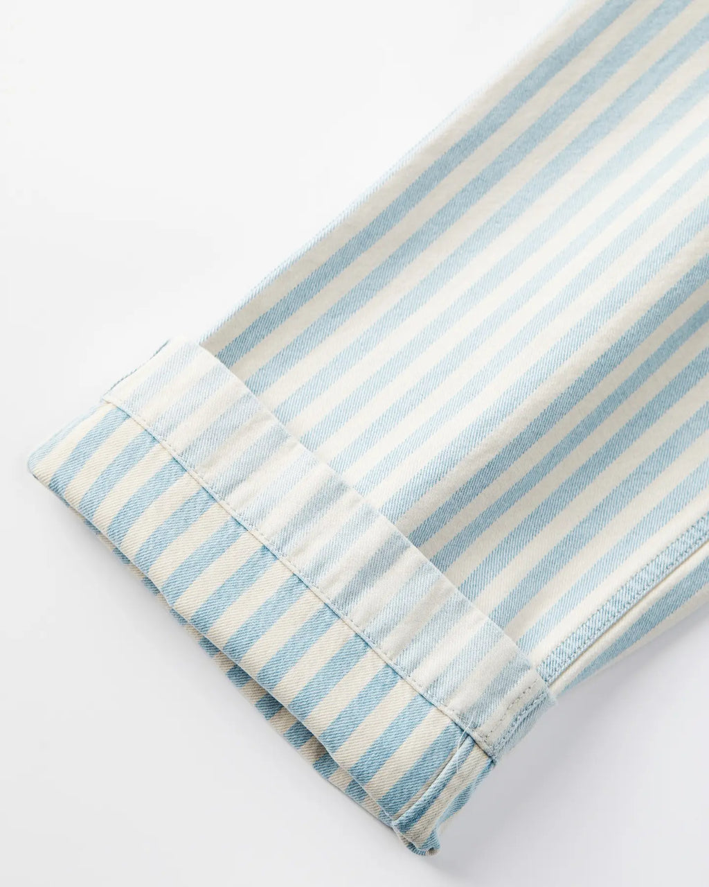 Détail bas de jean en denim léger rayé bleu ciel et blanc, coupe droite avec un ourlet cousu soigné, adapté à toutes les morphologies féminines.
