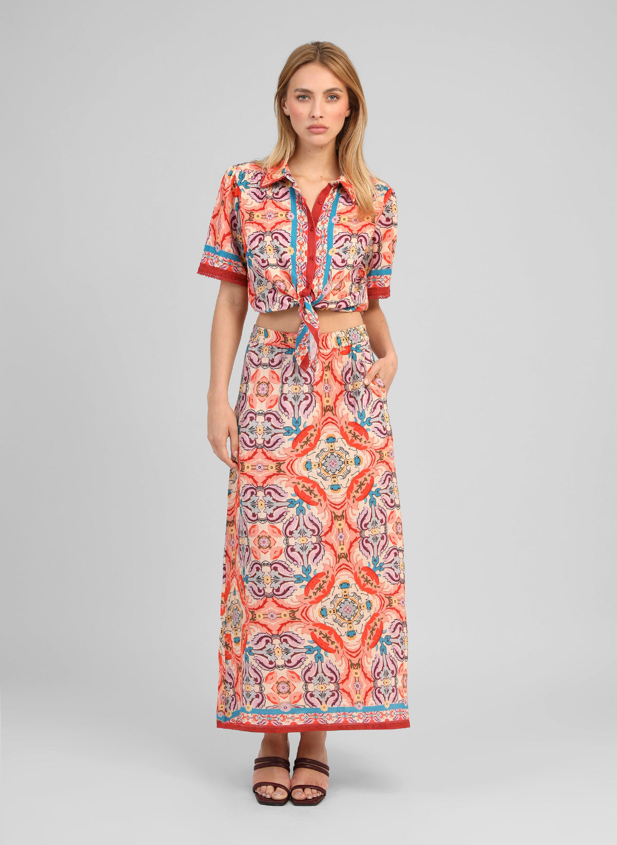 An'ge – Chemise Saturna Folka Corail, mannequin portant un ensemble chemise nouée et jupe longue à motifs colorés
