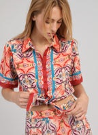 An'ge – Chemise Saturna Folka Corail, mannequin portant une chemise à motifs colorés nouée sur le devant