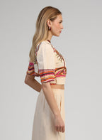 An'ge – Omlottopp Soriana Palmyre Rose, modell sedd från sidan klädd i broderad crop top och beige byxor
