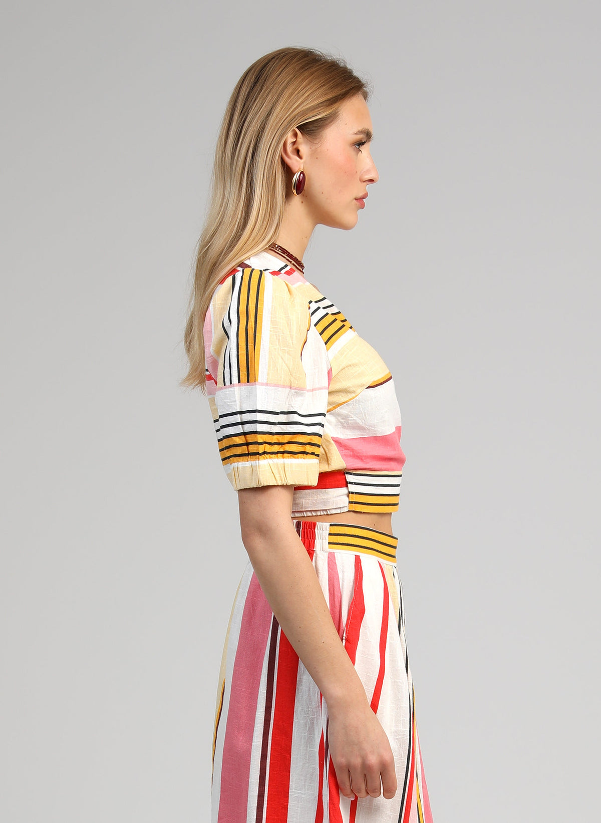 An'ge – Overslagtop Soriana Belinda Multico, model in profiel in een set van gestreepte meerkleurige top en rok
