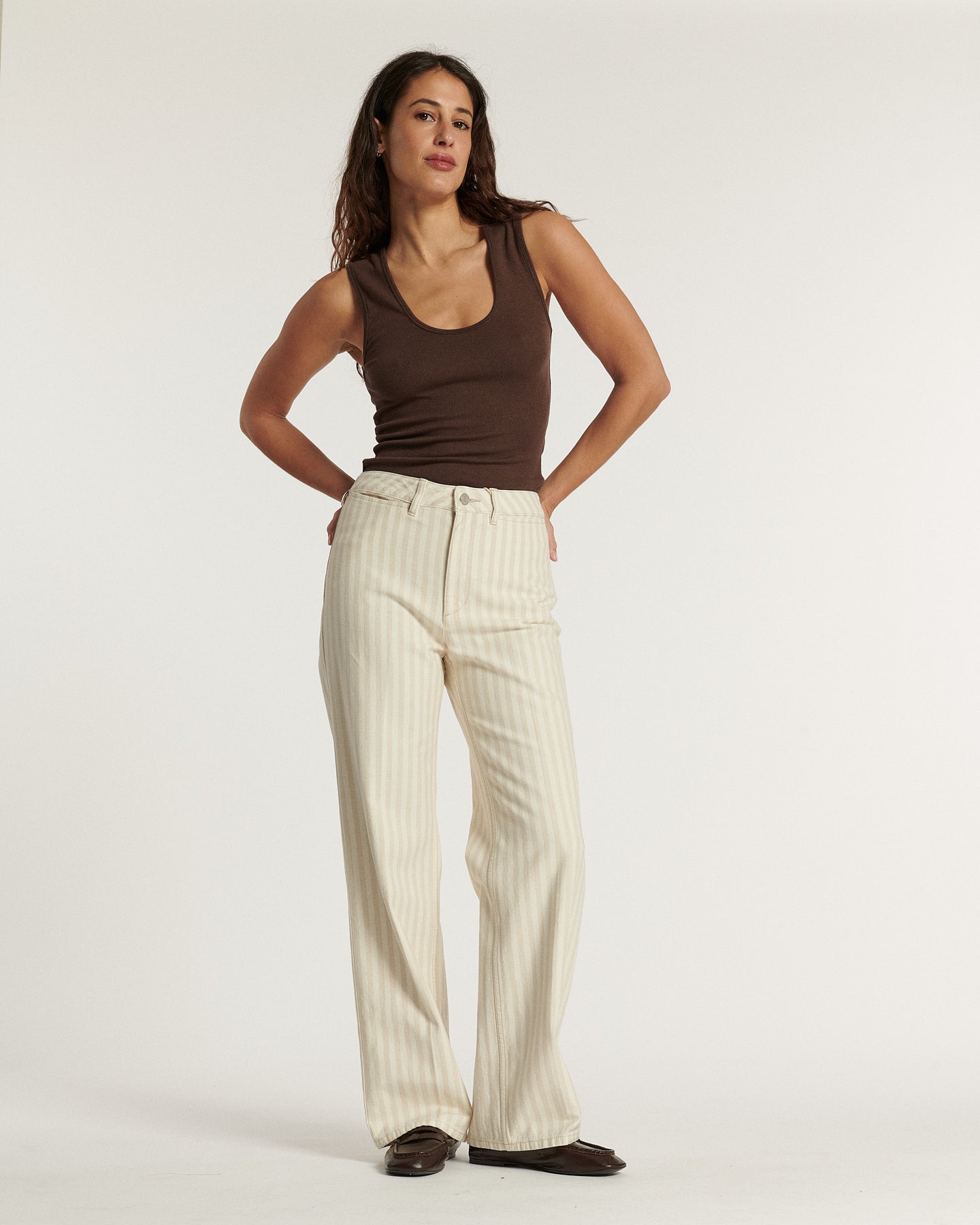Jean femme en coton beige clair à fines rayures verticales, coupe large et droite, offrant une silhouette fluide et confortable idéale pour l'été.