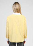 An'ge – Chemise Sylana Jaune, chemisier jaune à rayures blanches porté de dos par une femme blonde