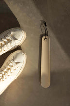 Schuhlöffel TILO in minimalist Gestaltung neben white Sneakern auf grauem Undertergrund.