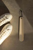 Schuhlöffel TILO in minimalist Gestaltung neben white Sneakern auf grauem Undertergrund.