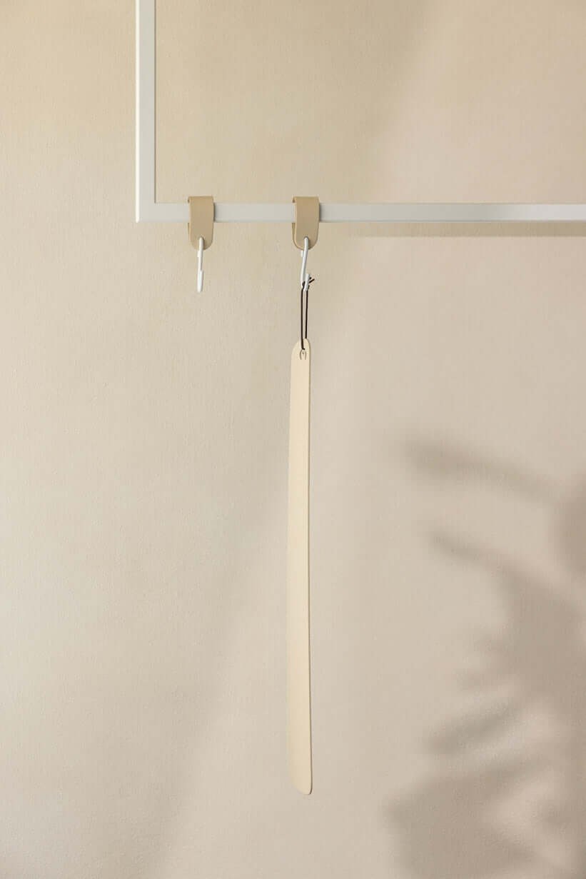 Schuhlöffel TILO aus high-quality metall an einem minimalistischen Haken in modernm Interior.